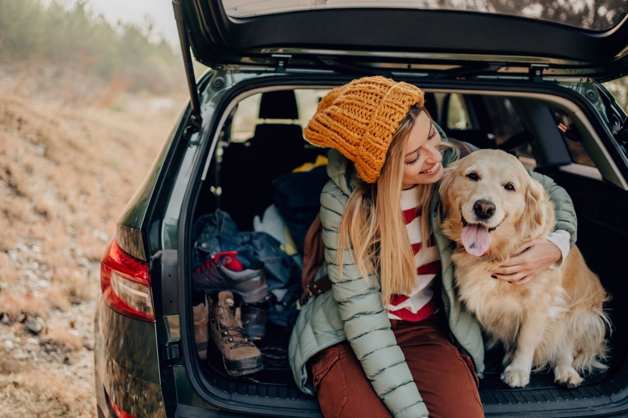 a girl hugging her dog in the back of her car