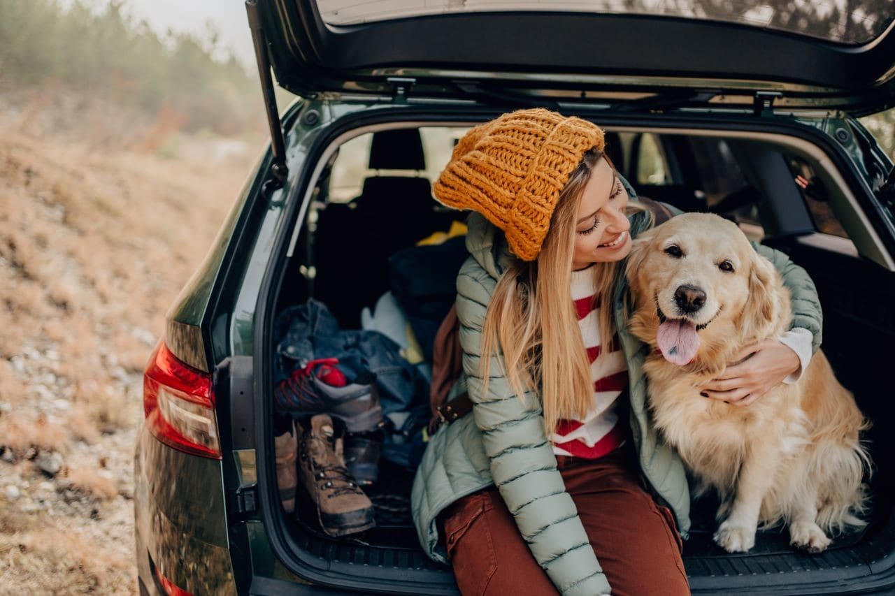 a girl hugging her dog in the back of her car